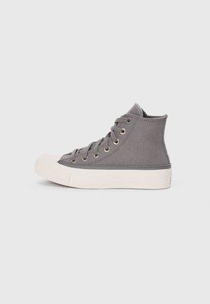 Høy topp grå lær-sneaker med gummisåle, metallhull, og flate lisser. Har en hvit tåhette og detaljer på midtsålen.