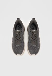 Scarpe da ginnastica grigie con tomaia in rete, punta rotonda e suola piatta in gomma. Caratteristiche includono lacci e un tassello sul tallone.