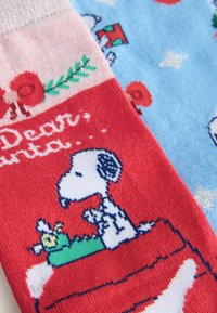Red and blue knitted socks featuring Snoopy and a bunny, floral and snowflake patterns, with a sparkly cuff and "Dear Santa" text.