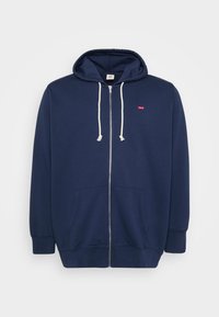 Marineblå hettegenser med glidelås laget av en bomullsblanding, med snorhette, frontlommer og en liten rød logo på brystet. Myk tekstur.