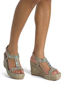 Des sandales compensées avec une semelle en jute tress�é, des lanières métalliques et des accents de bijoux multicolores dans un motif floral. Design à bout ouvert.