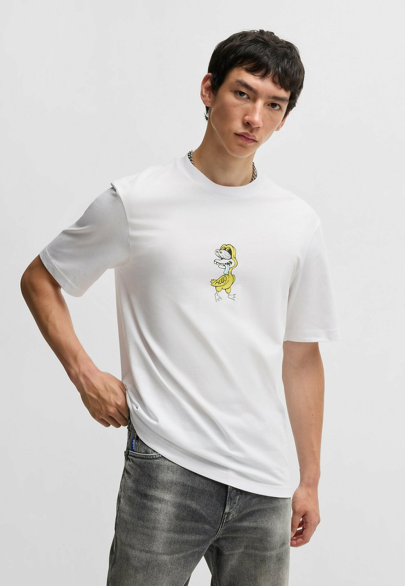 Hvid kortærmet t-shirt lavet af bomuld, med et tegneserie-design af en and i en gul regnfrakke på brystet.