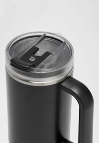 Črn potovalni kozarec iz nerjavnega jekla s prozornim plastičnim pokrovom. Ima drsno zapiranje, srebrni dekorativni pas in trden ročaj.