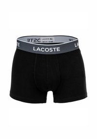 Boxer in cotone nero con elastico grigio che presenta il logo "LACOSTE" in bianco, progettati con una vestibilità aderente e dettagli di cucitura minimi.