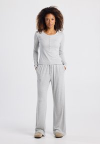 Grijs loungewear-set met een langemouwtop met knoopsluiting en losse broek met elastische tailleband. Zacht, lichtgewicht stof.
