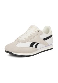 Kopačky Reebok s béžovým zamatom a bielou koženou hornou časťou, čiernymi akcentmi, polstrovaným golierom a textúrovanou čiernou gumovou podrážkou.