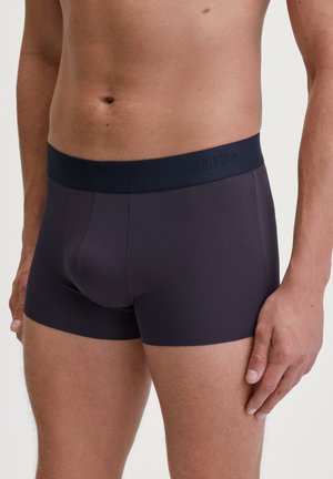 Boxer-briefs pour hommes en gris foncé, fabriqués à partir d'un tissu lisse et extensible. Dotés d'une ceinture marine avec le logo "CALIDA" en relief.