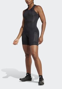 Black athletic onesie with a fitted design, textured panels, and a zip front. Features three dark stripes on the sides and a padded seat.