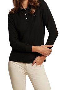 Černá polokošile s dlouhým rukávem a klasickým límečkem, se třemi knoflíky a vyšitou postavou na hrudi. Nosí se s světlými džíny.