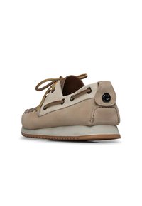 Scarpa da barca in suede beige chiaro con design lace-up, accenti marroni a contrasto, suola in gomma e dettaglio del logo circolare sul tallone.