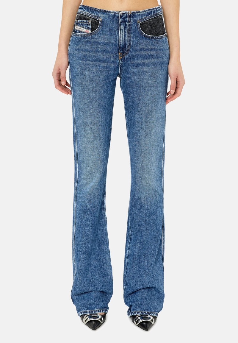 Jeans in denim blu aderenti con una forma svasata, caratterizzati da dettagli in denim scuro sulle tasche e una chiusura a bottone classica. Texture sfrangiata vicino all'orlo.