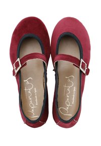 Zapatos Mary Jane de ante rojo con un borde elástico negro y una hebilla decorativa plateada en la correa. Diseño plano con punta redondeada.