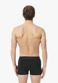 Boxers en coton noir avec une texture lisse et une taille élastique arborant un logo ton sur ton. Vue de l'arrière, sans motifs ni accents distincts.