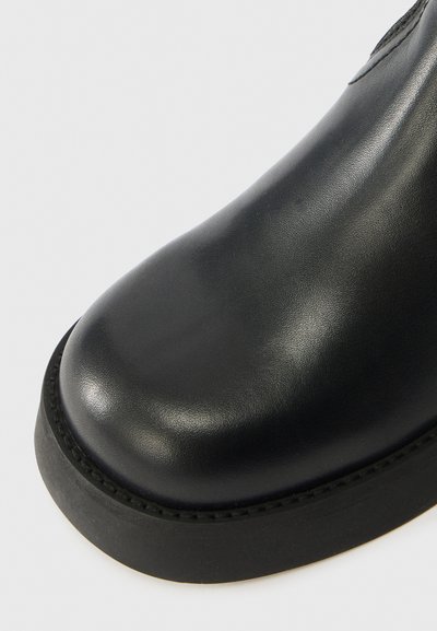 Μαύρο δερμάτινο μποτάκι με στρογγυλή μύτη, λείος υφασμάτινος σχεδιασμός και παχύ καουτσούκ σόλα. Δεν εμφανίζονται ορατά εξαρτήματα ή σχέδια.