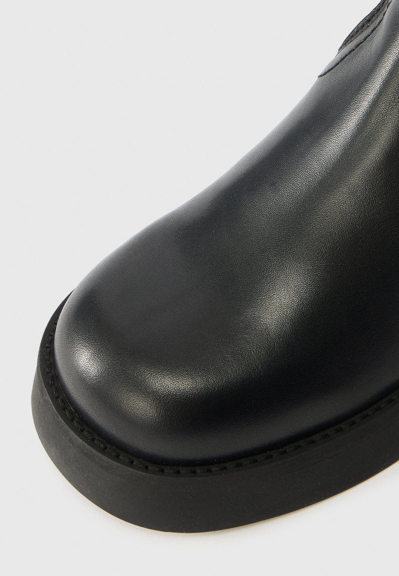Sort læderstøvle med rund tå, glat overflade og en tyk gummisål. Ingen synlige metaldele eller mønstre er vist.