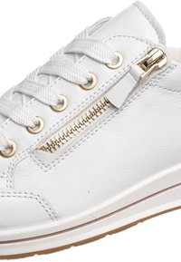 White leather sneaker with white laces, gold eyelets, and a gold side zipper on a white sole with a brown tread.