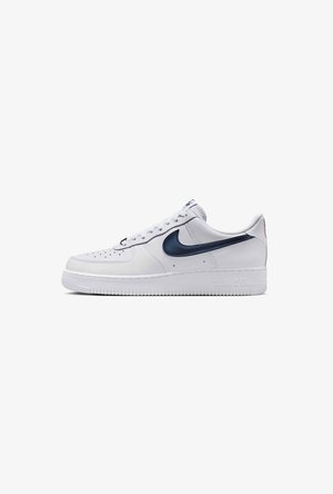 Witte lage Nike Air Force 1 sneaker met marineblauwe swoosh-logo en geperforeerde neus op witte achtergrond.
