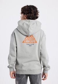 Gray hoodie with a large orange triangular logo on the back, featuring "COLORADO TRAIL CLUB 1989." Soft fabric and a hooded design.