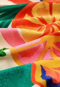 Stof med livlige frugtmønstre i orange, pink, gul og grøn. Struktureret overflade med en blød, glat fornemmelse.