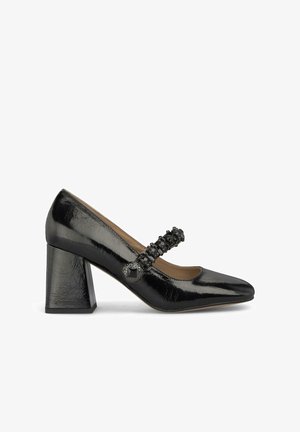 Scarpa nera in vernice con tacco alto, punta affusolata, spesso tacco quadrato e una fascia decorativa con dettagli testurizzati neri.