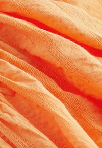 Oranssi, kevyt kangas, jossa on pehmeä, läpikuultava pinta. Ominaisuuksia ovat hieman rypistynyt pinta ja hienovarainen ruutukuosi koko ajan.