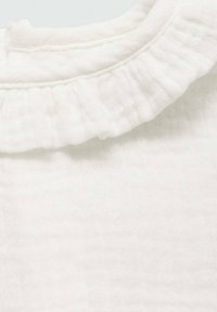 Bela bombažna tkanina z teksturirano površino, ki vključuje volanasti ovratnik in subtilno šivanje ob robovih. Mehka in lahka material.