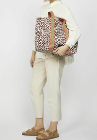 Torebka typu tote z brązowym wzorem w panterkę, solidnymi zielono-pomarańczowymi uchwytami w paski, prostokątnym kształtem i teksturowanym materiałem.