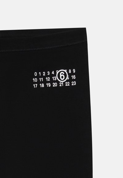 Svarta leggings med en vit numrerad skala från 0 till 23, där siffran 6 är markerad, ovanför en slät, elastisk yta.