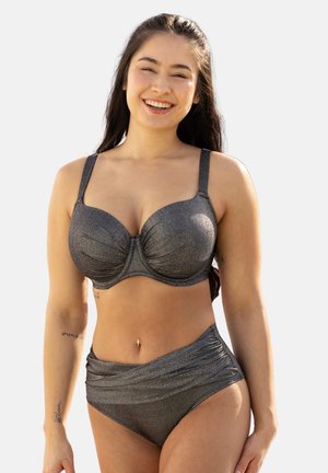 Lächelnde Frau mit langen dunklen Haaren, die einen glänzenden dunkelgrauen Bikini mit stützendem Bügel-Oberteil und hochgeschnittenem Unterteil trägt.