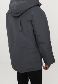 Ciemnoszary, ocieplany płaszcz z kapturem, z sznurkiem ściągającym, prostym kroju i długimi rękawami. Tylny widok pokazuje prostą, schludną wykończenie.