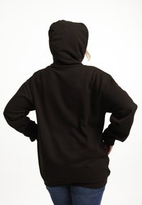 Felpa nera con una vestibilità ampia, caratterizzata da un grande cappuccio e maniche lunghe. Il tessuto sembra morbido, con una trama uniforme e senza motivi visibili.