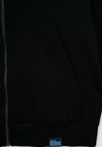 Czarna bluza rozpinana z kieszeniami z przodu, ściągaczami przy mankietach i u dołu. Posiada niebieską metkę akcentującą na dole. Gładka tekstura, swobodny design.