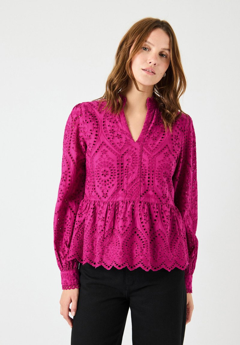Blusa fucsia con scollatura a V, maniche lunghe e vita peplum. Presenta intricati motivi a occhiello e un orlo a scaglie.