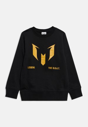 Hanorac negru cu un logo stilizat „M” auriu și cuvintele „LEGENDĂ” și „THE G.O.A.T.” imprimate sub logo în partea din față.