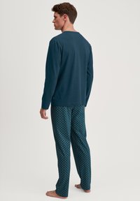 Haut à manches longues bleu marine associé à un pantalon sombre à motifs bleu foncé avec des designs géométriques bleu clair, fabriqué en tissu doux et respirant.