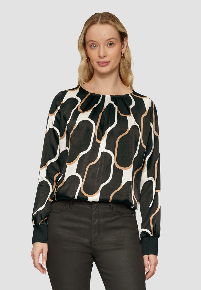 Blouse noir et blanc avec des motifs abstraits en vagues beige, présentant un col froncé et des manches longues avec des poignets noirs.