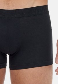 Black boxer briefs made of soft, stretchy cotton. Features a thick, embossed waistband and fitted design for comfort and support.
