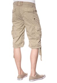 Pantaloni cargo beige con più tasche, orli arrotolati e cordini regolabili, realizzati in cotone resistente. Abbinati a sneakers beige.