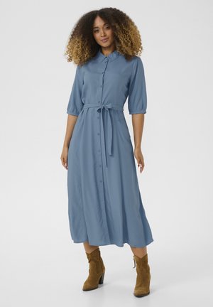 Button-up, midi dress in light blue fabric with a belted waist, puff sleeves, and a straight skirt. Pair with brown suede ankle boots.
