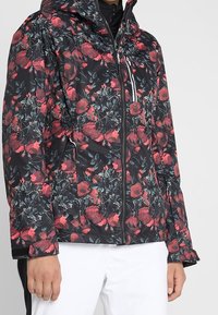 Schwarze gepolsterte Jacke mit einem floralen Muster in Rot und Grün, mit Reißverschluss und Kapuze, geeignet für den Außenbereich.