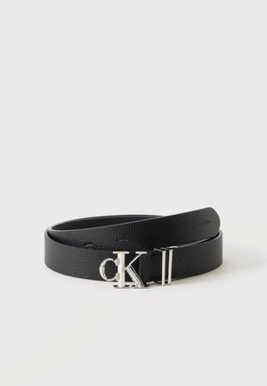 Ceinture en cuir noire avec une boucle logo Calvin Klein "CK" argentée, roulée sur un fond clair uni.