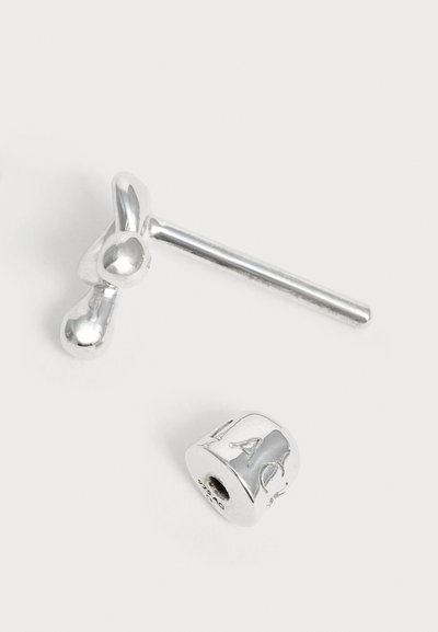 Clou d'oreille en argent en forme de nœud avec un fermoir papillon cylindrique séparé sur fond blanc.