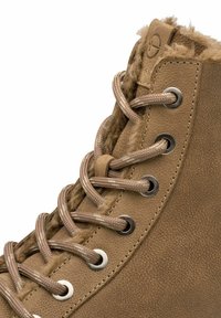Braune Lederstiefelette im High-Top-Stil mit Kunstfellfutter, metallischen Ösen und runden Schnürsenkeln für einen sicheren Halt. Texturierte Oberflächendetails sind sichtbar.