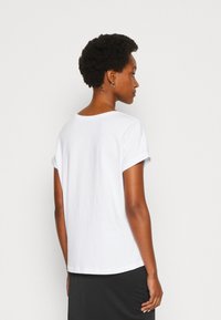 White cotton t-shirt with rolled short sleeves, round neckline, and a relaxed fit. Fabric appears soft and smooth.