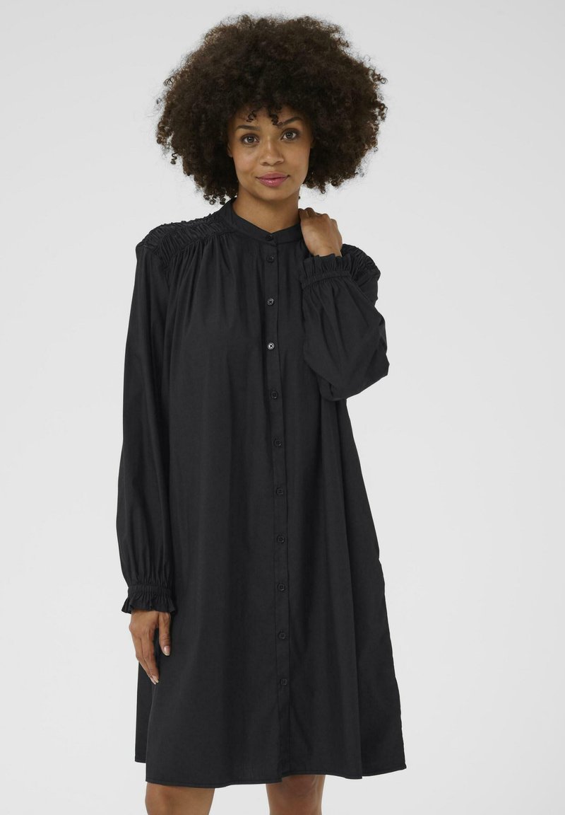 Robe noire à boutons, faite d'un tissu doux, avec un design de manche froncée, des manches bouffantes longues et une coupe décontractée.