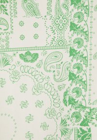 Motivi floreali verdi e paisley con foglie e forme decorative su uno sfondo di tessuto bianco.