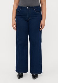 Mørkeblå vid jeans med høj talje, med klassisk fem-lommer styling, bæltestropper og subtile syninger.