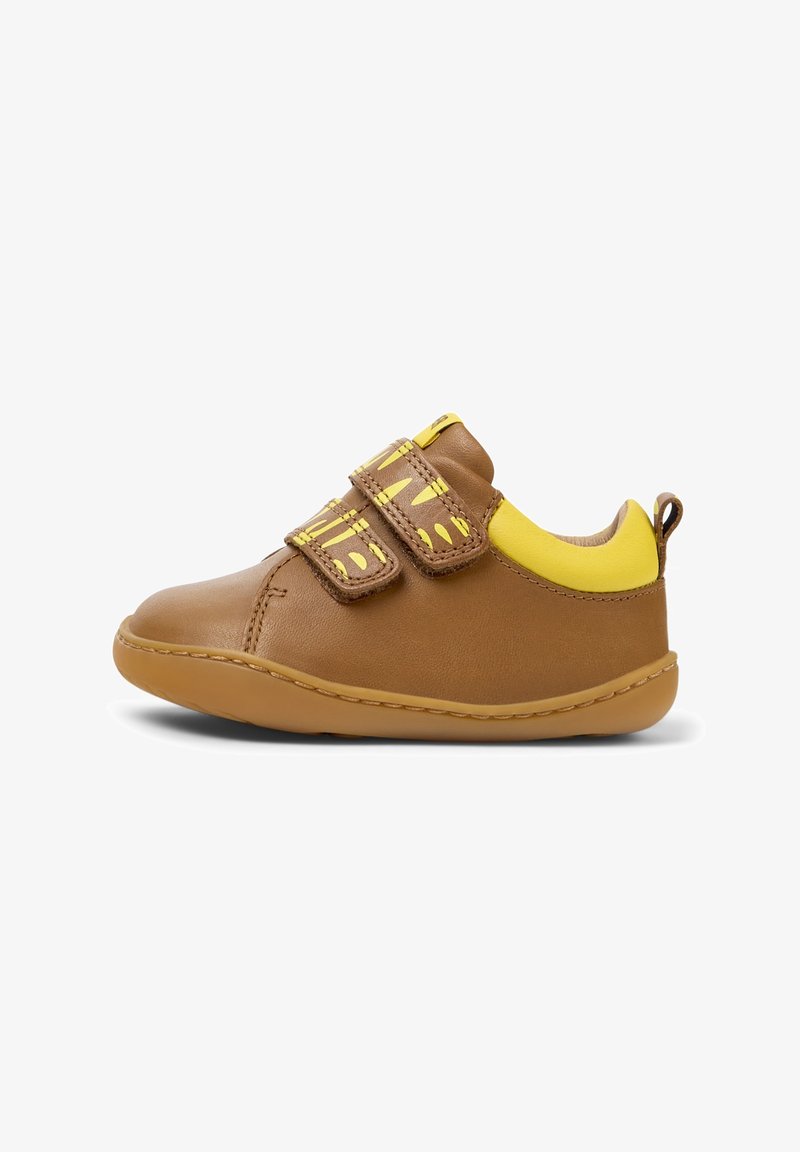 Chaussure marron pour tout-petit avec col rembourré jaune et deux bandes Velcro jaunes à motifs sur fond blanc.
