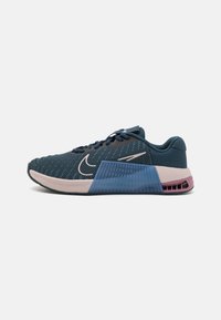 Athletische Sneaker mit einem dunkelblauen Mesh-Obermaterial, einer hellrosa Zwischensohle, durchsichtigen blauen Seitenakzenten und einem lila hinteren Abschnitt.