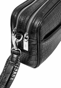 Czarna torebka z tłoczonej skóry krokodyla z podwójnymi srebrnymi zamkami błyskawicznymi, odpinanym paskiem i gładką fakturą. Smukły prostokątny kształt o błyszczącym wykończeniu.